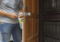 Locksmith installing a door knob lock cylinder on a wooden front door during a service call